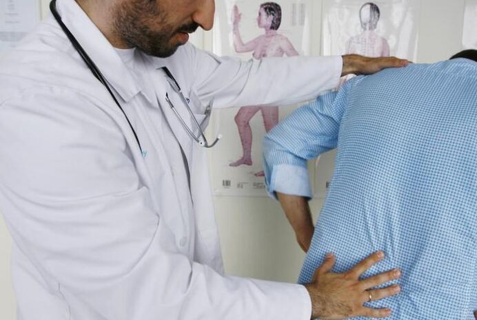 Doctor examines a patient with back pain in the lumbar region